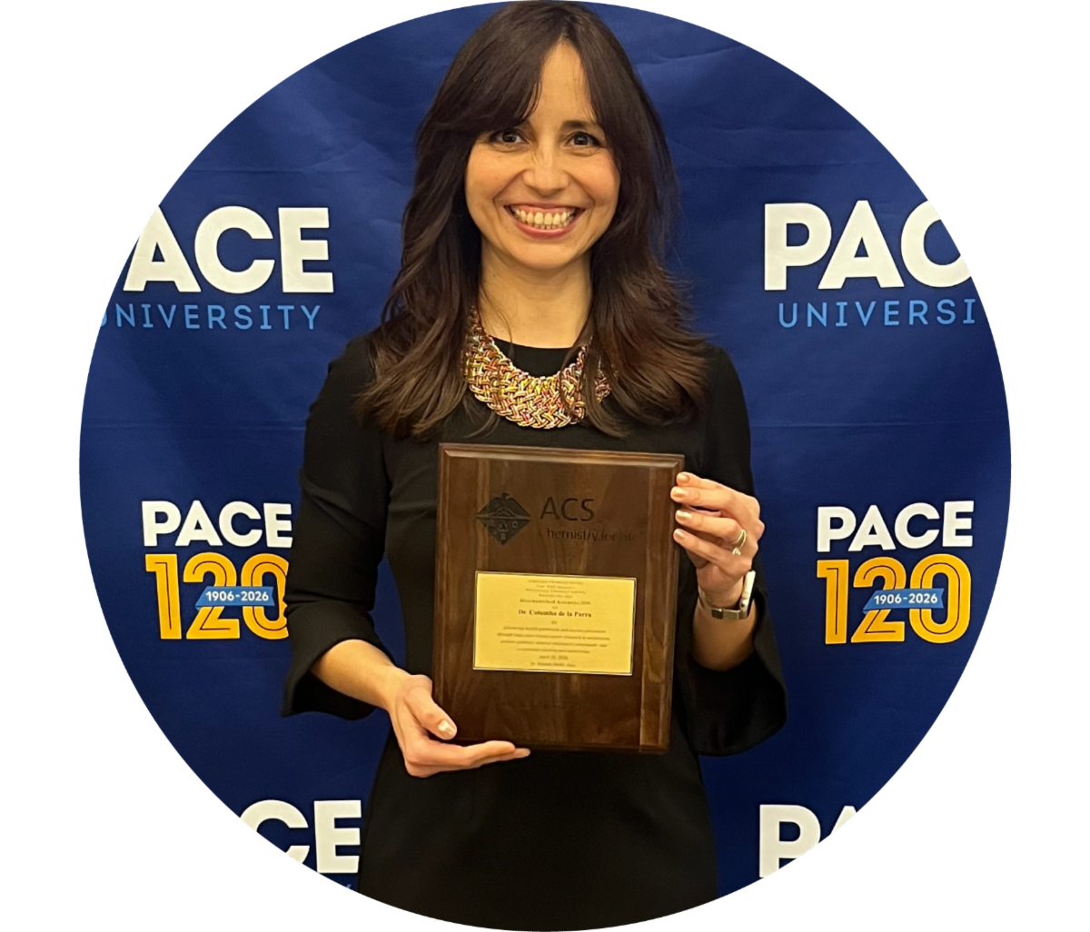 Professor with award in front of Pace U Step and Repeat