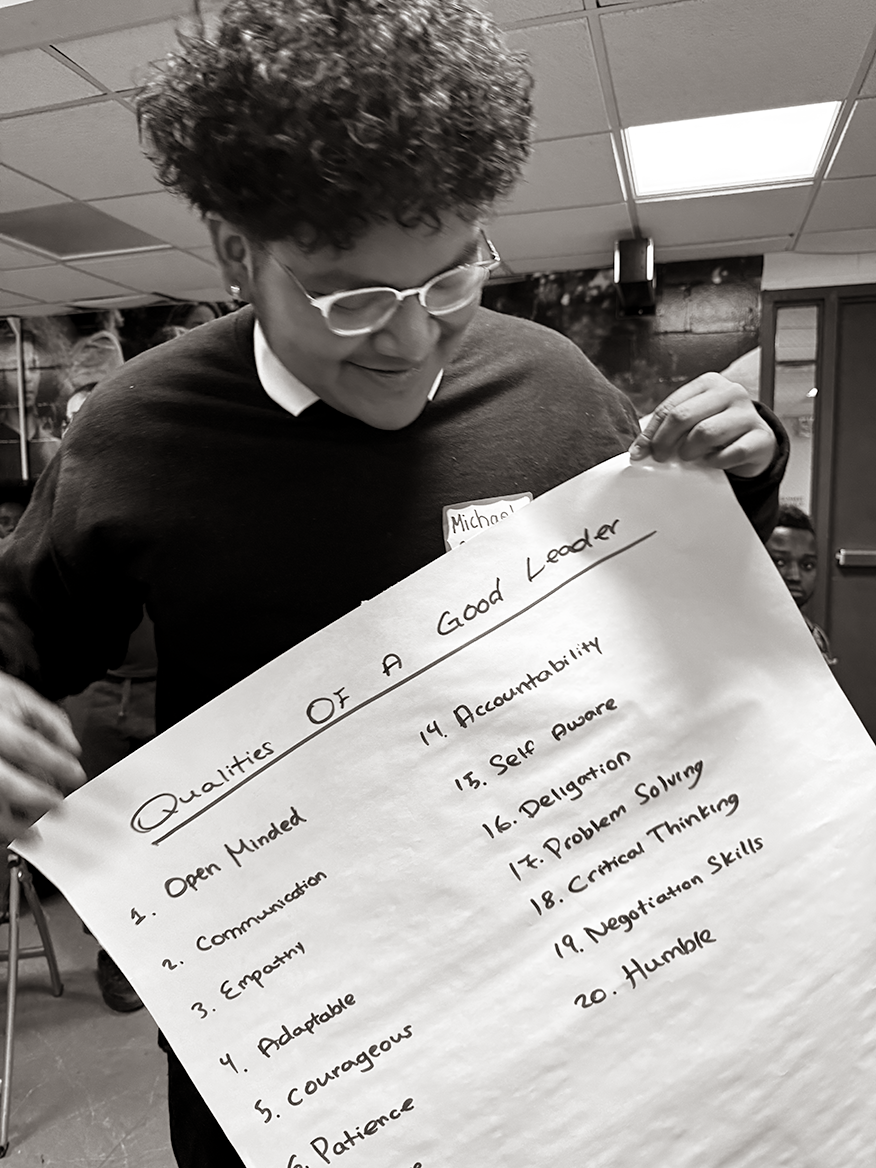 A student leader displays a poster outlining key leadership qualities.