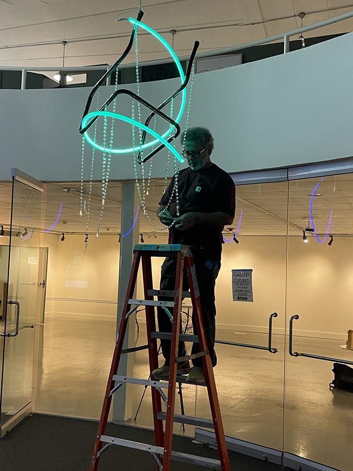 Photo of artist with chandelier in blue