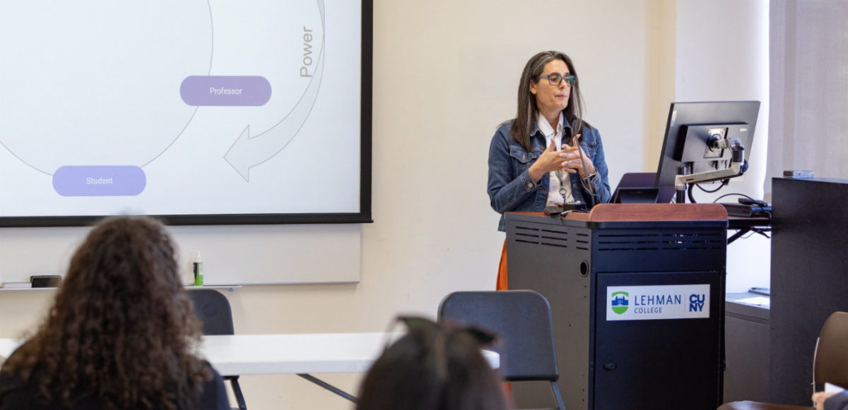 Professor Alyshia Gálvez stands at a podium with a graphic showing student faculty power relationship