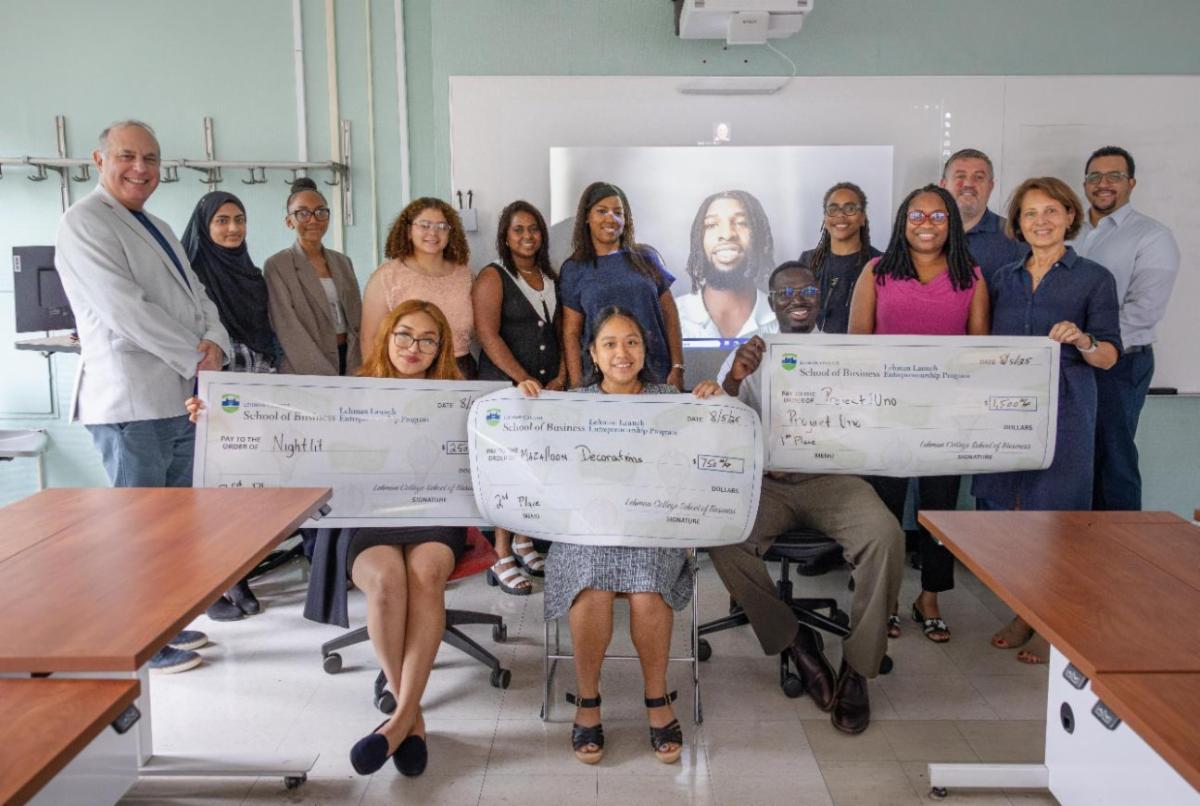 A group photo including the three School of Business students business pitch awardees with their checks