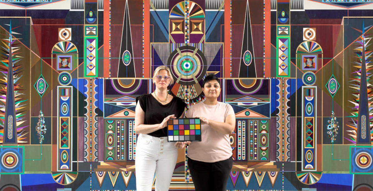 Ornate tile mural in the background of portrait of two artists holding square colorful tiles