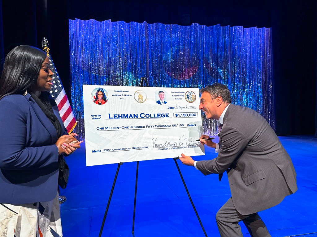 Dinowitz signs a giant check after Vanessa L. Gibson 