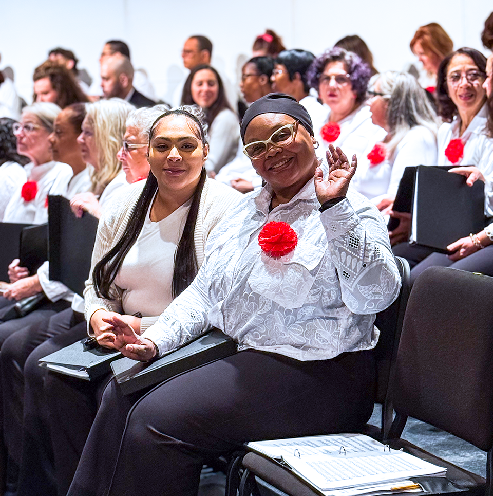 Waving hello wearing bright white top with red flower
