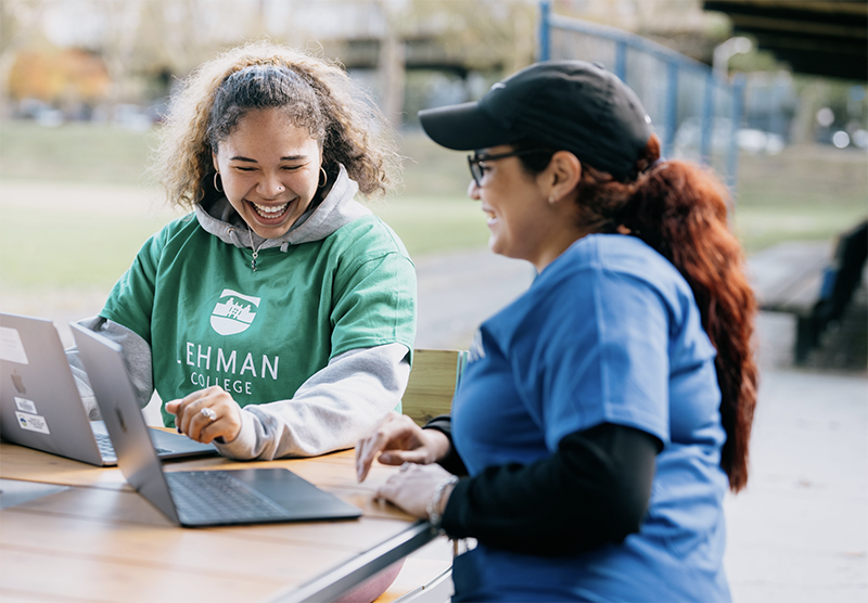 Two Students Smile at Laptops