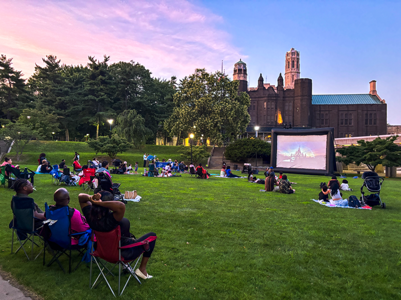 Photo of families on the lawn of the QUAD during sunset enjoying a movie at Lehman Stages family movie night