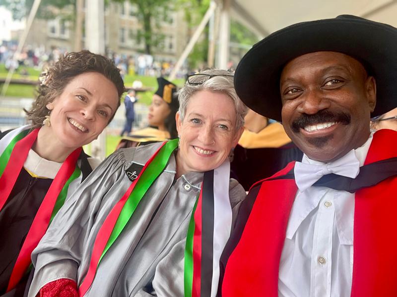 Three faculty members in regalia smile
