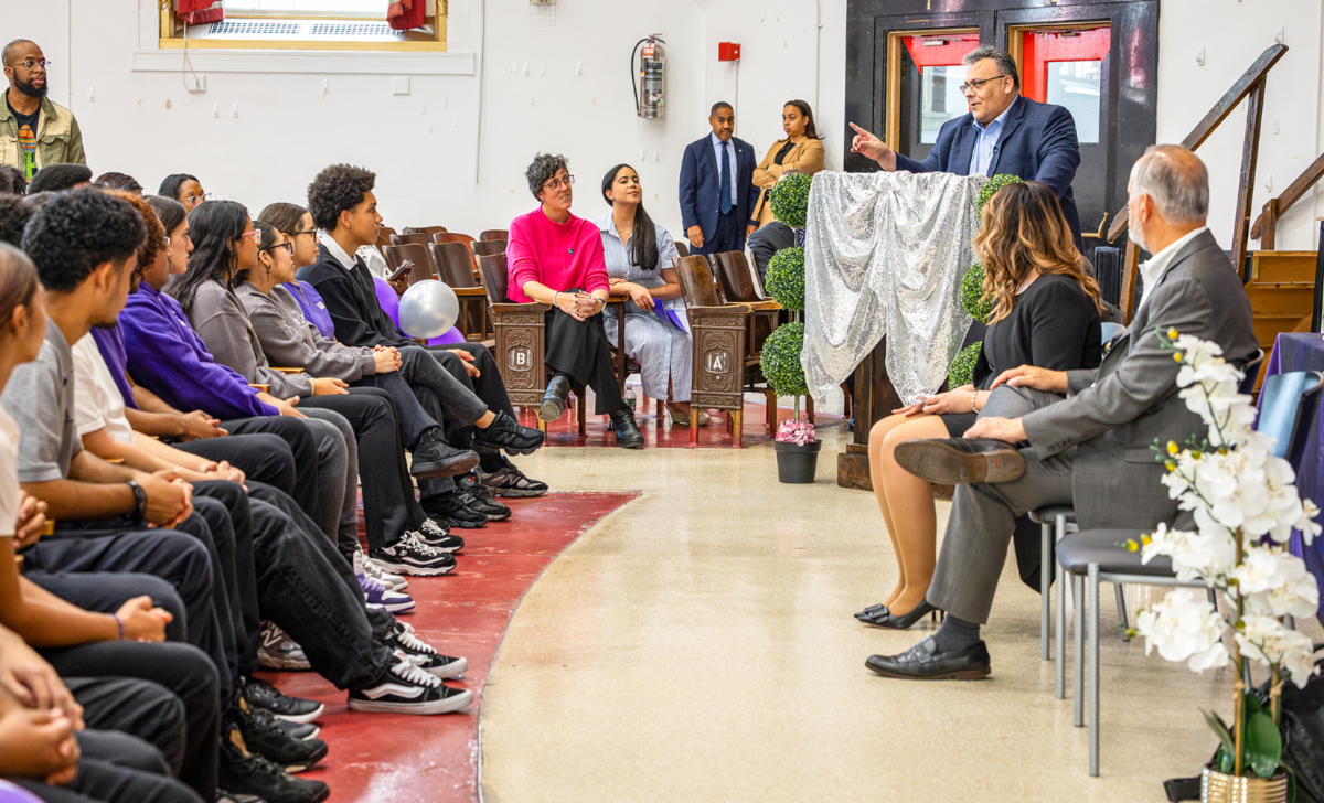 Delgado gestures from the podium while engaging students during a high school event
