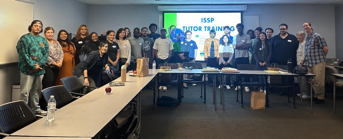 Group photo in front of a projector screen reading ISSP Tutor Training