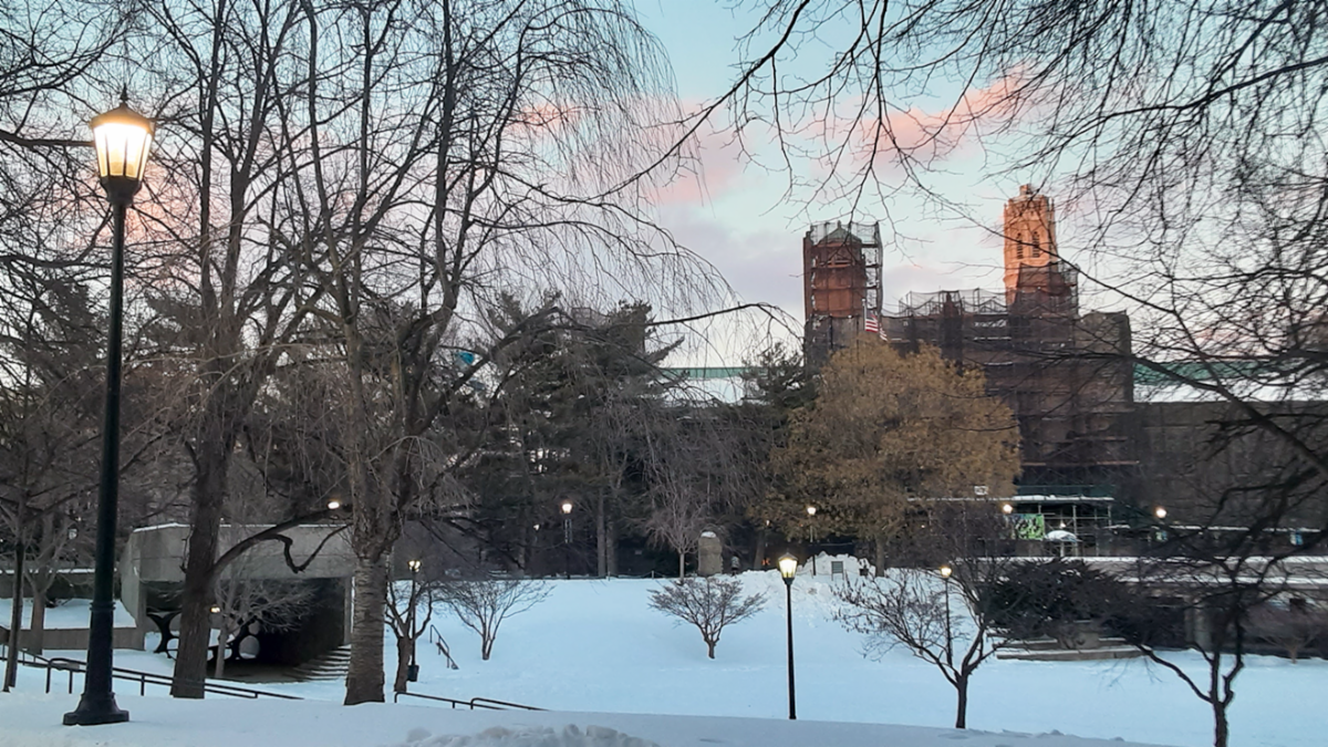 Music building under scaffolding with quad in foreground and blue and pink sunset
