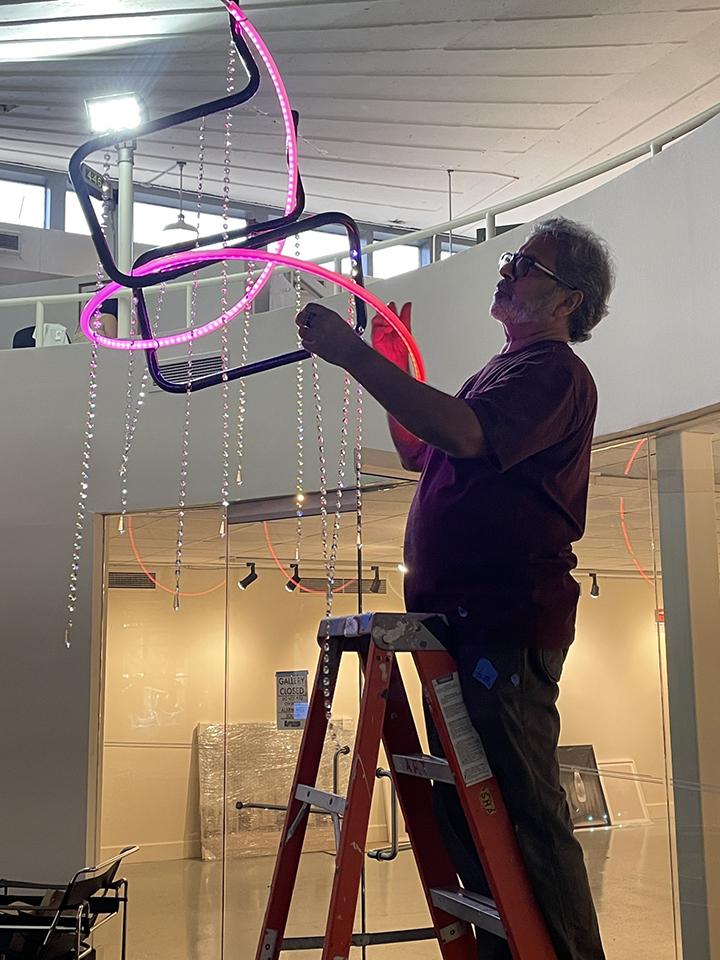 Photo of artist with chandelier in magenta