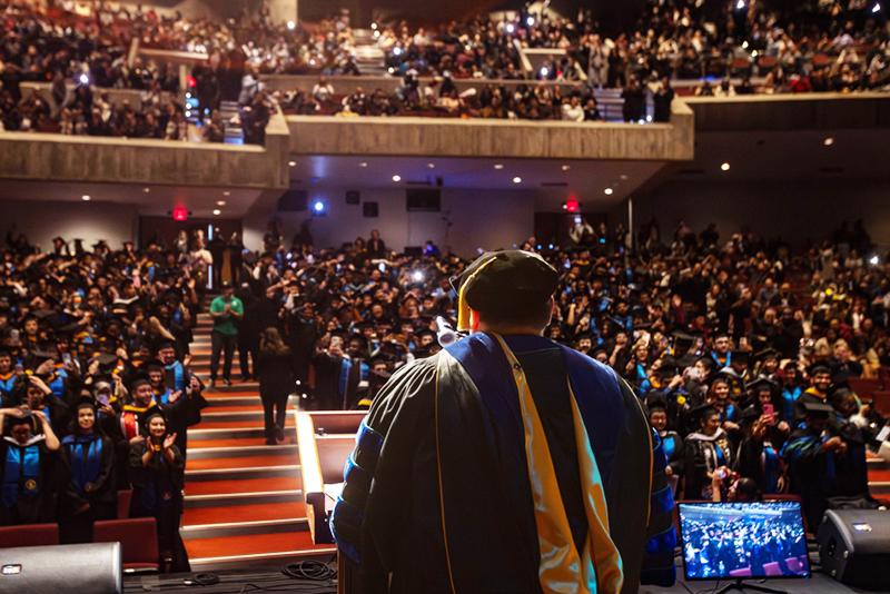 View of audience of graduates and families from behind president.