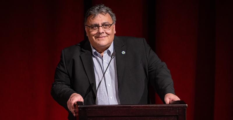 President Delgado at podium with red curtain backdrop
