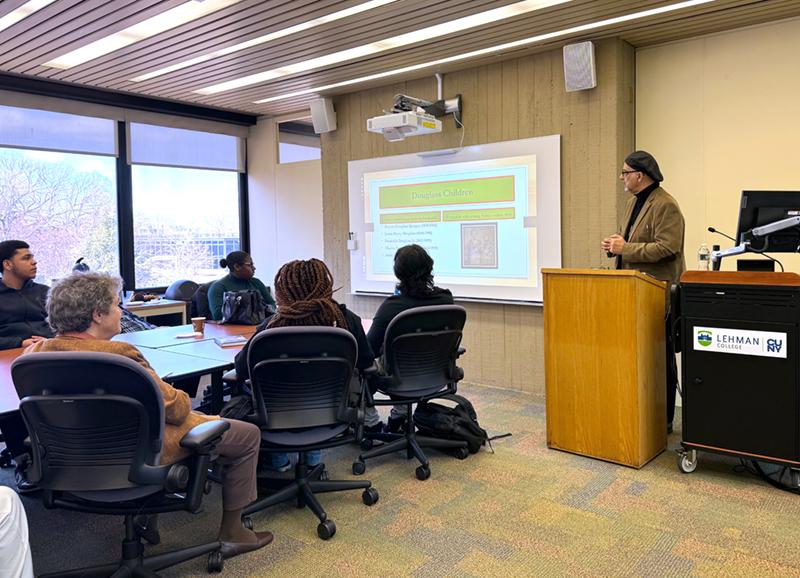 Group around conference table in windowed room speaker with presentation