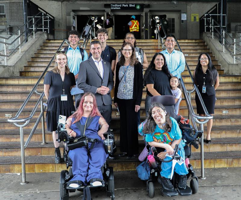 Group poses on and by the subway stairs just off campus