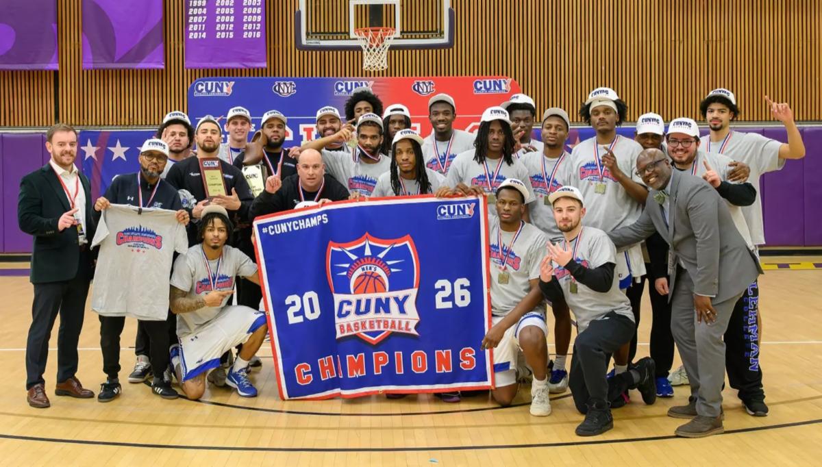 Mens basketball team poses for a photo on the court with banner