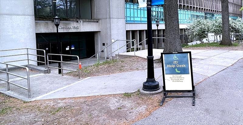 A sandwich board sign points down to the lower carman entrance