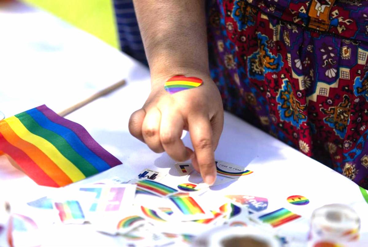 Rainbow stickers and flags and a student's hand with rainbow heart