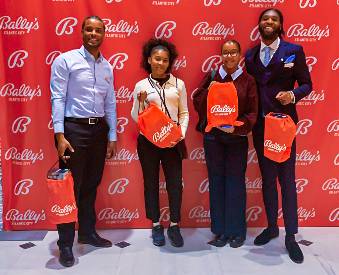 Group shot in front of a red bally's step and repeat