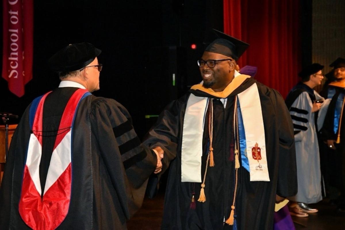 Graduate Benjamin Pinckney shaking hands with dean