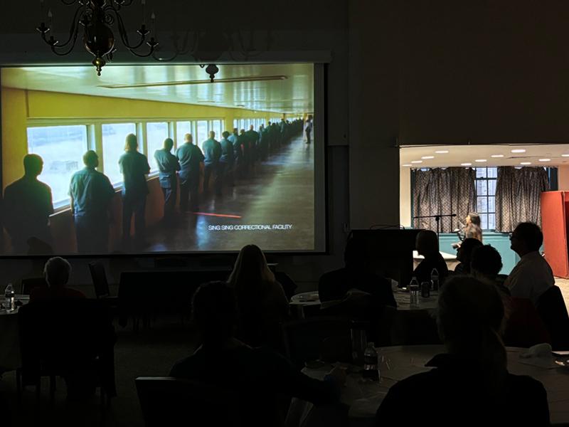 Movie on screen, silhouetted viewers in the dark