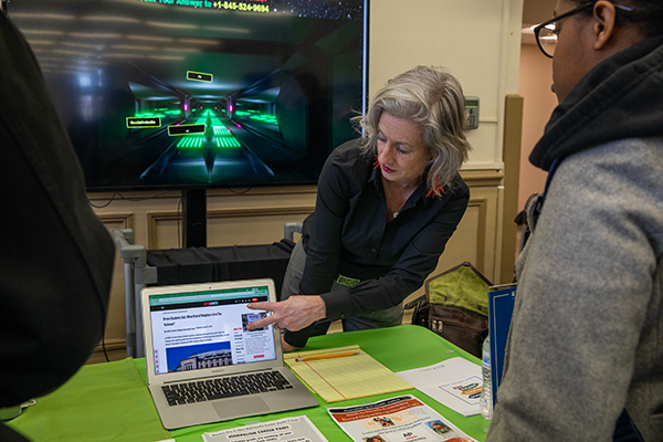 Prof pointing to laptop and student listening