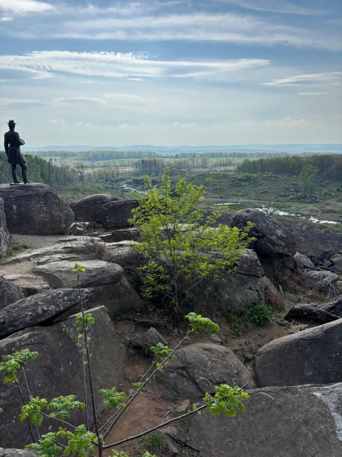 Soldier looking at landscape from rock formation