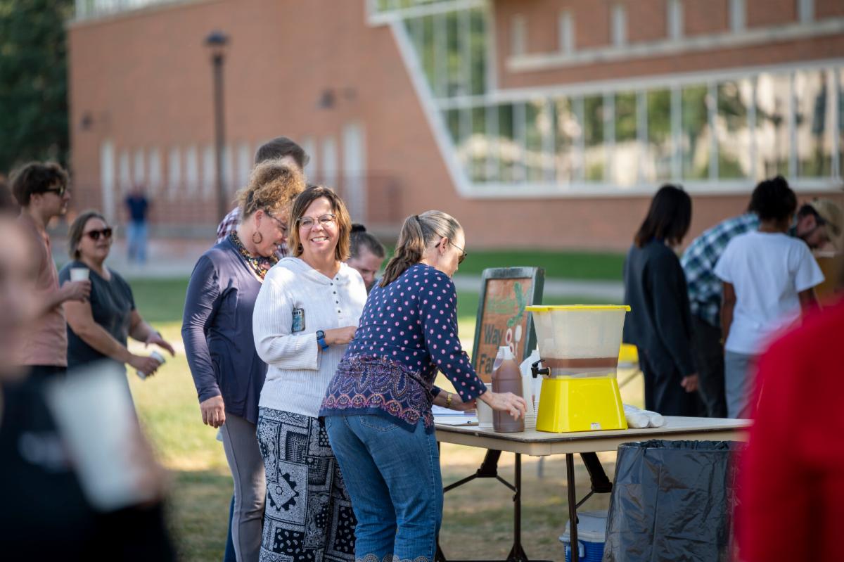 Staff members enjoy social hour on the quad on a sunny day