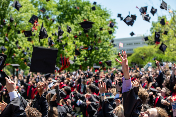 Graduates toss hats in the air.