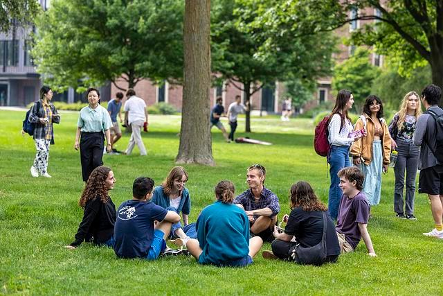Students standing and sitting on the grass