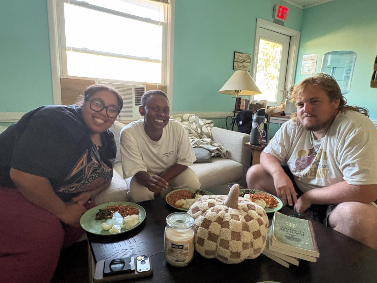 3 young adults around a coffee table with dinner