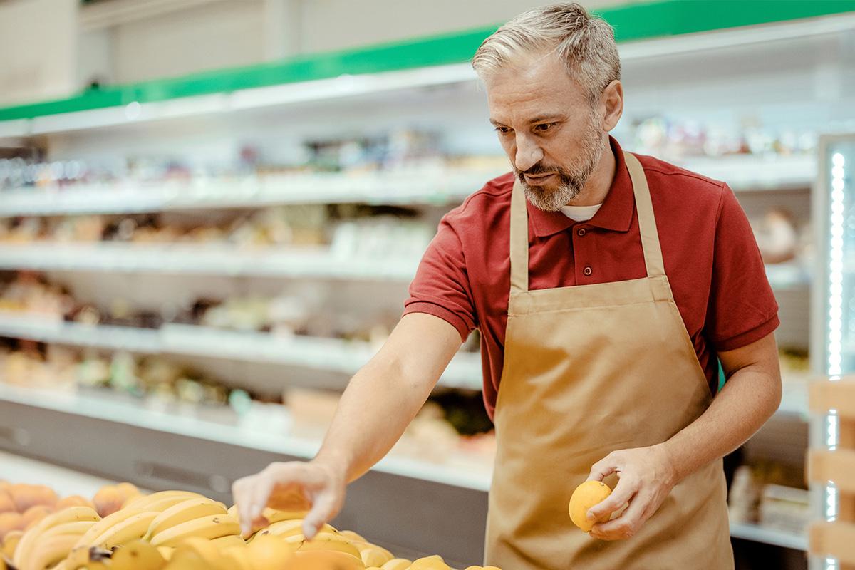 grocery store employee stocking bananas
