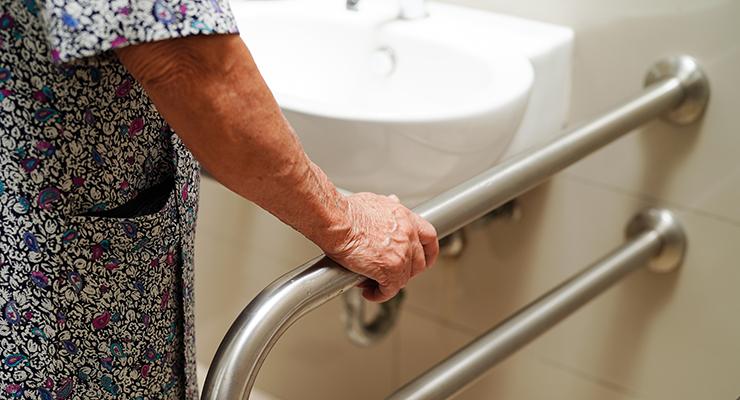 older woman holding grab bar by sink