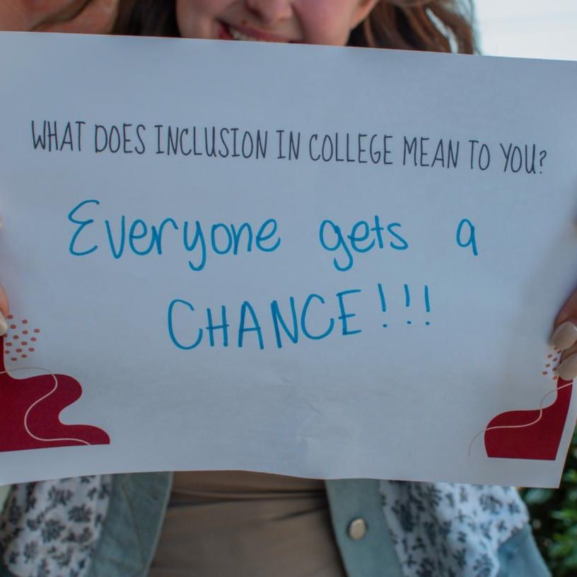 Person holding a sign over their face with the IPSE logo and the sign reads What does inclusion in college mean to you  Everyone gets a chance