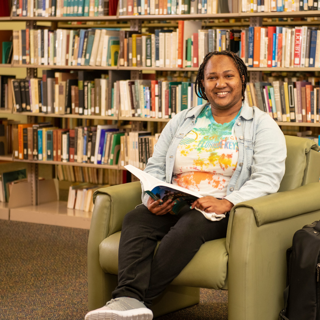 Student sitting down and reading a book in a library