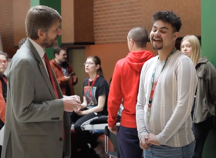 staff person speaking with a student in a busy room