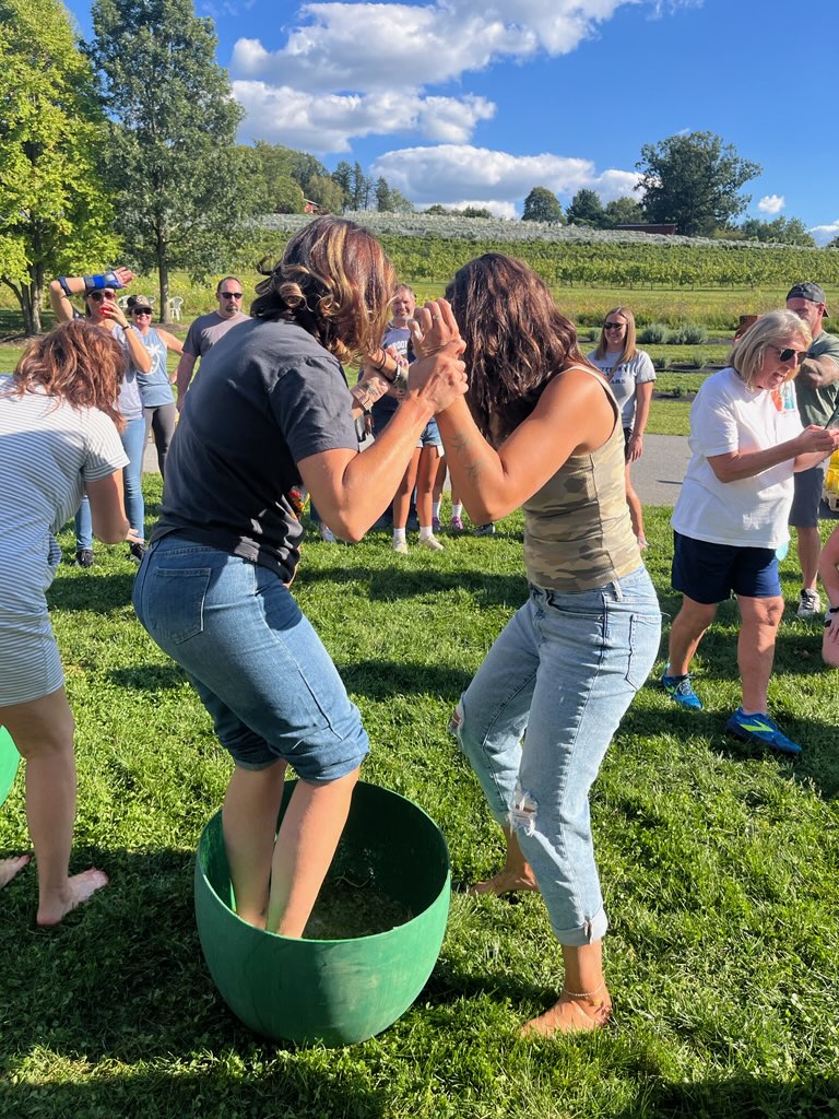 Two women crushing grapes with their feet in a green bucket