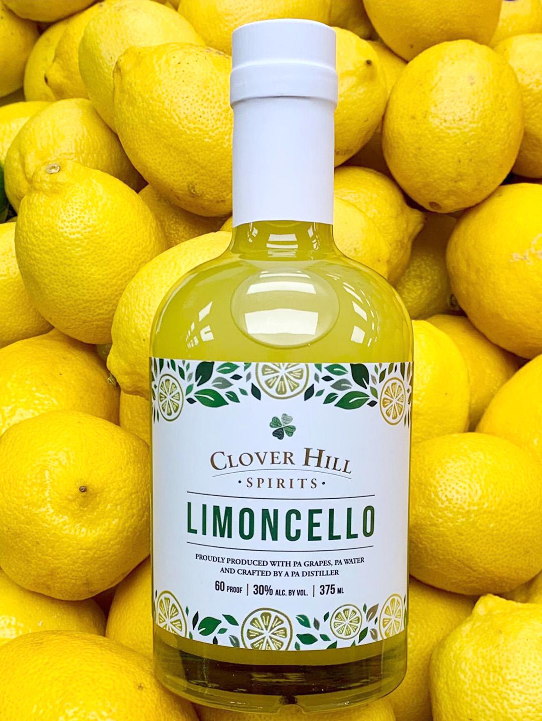 Bottle of Clover Hill Spirits Limoncello lying on a stack of lemons