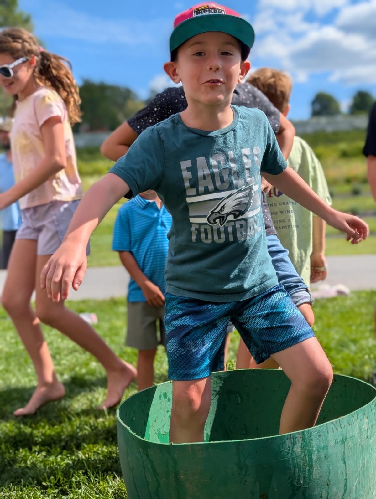 Young boy stomping grapes in a half barrel at Clover Hill Vineyards & Winery