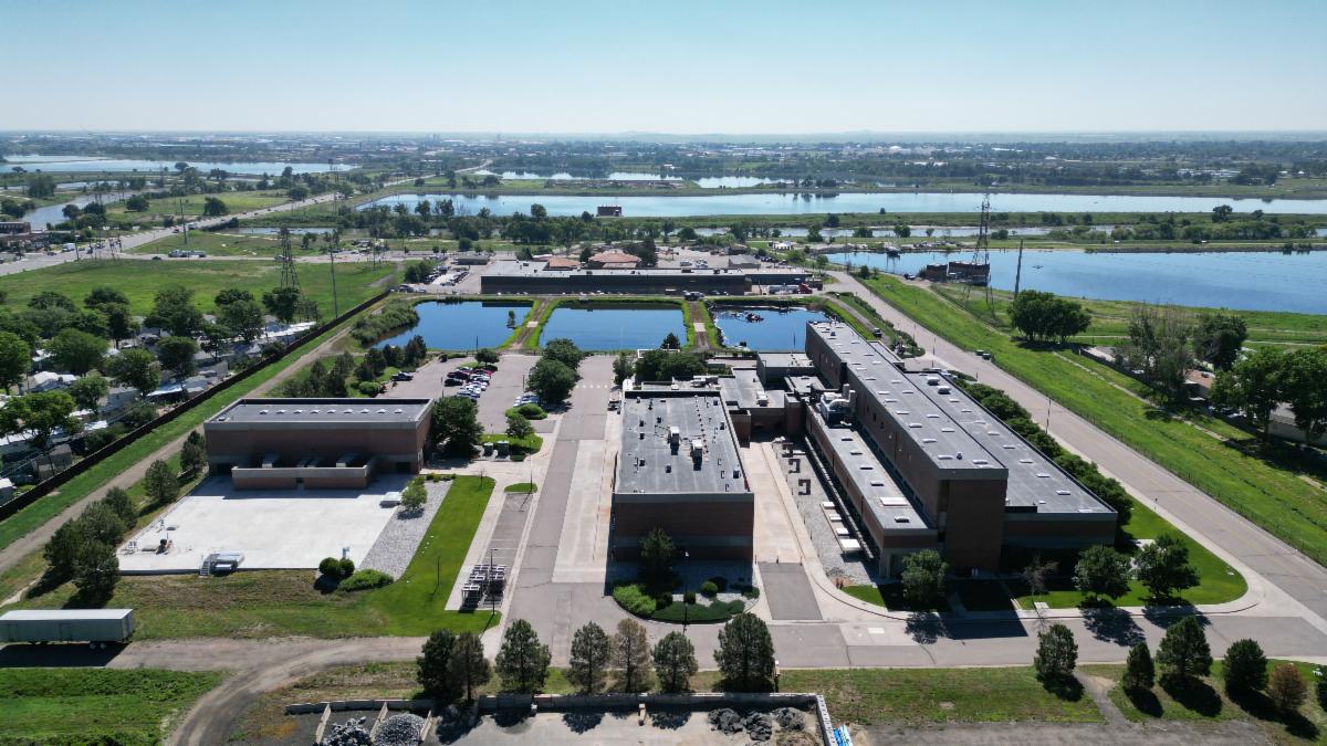 Aerial photo of a large building with small square ponds outside, and larger ponds and green grass nearby.