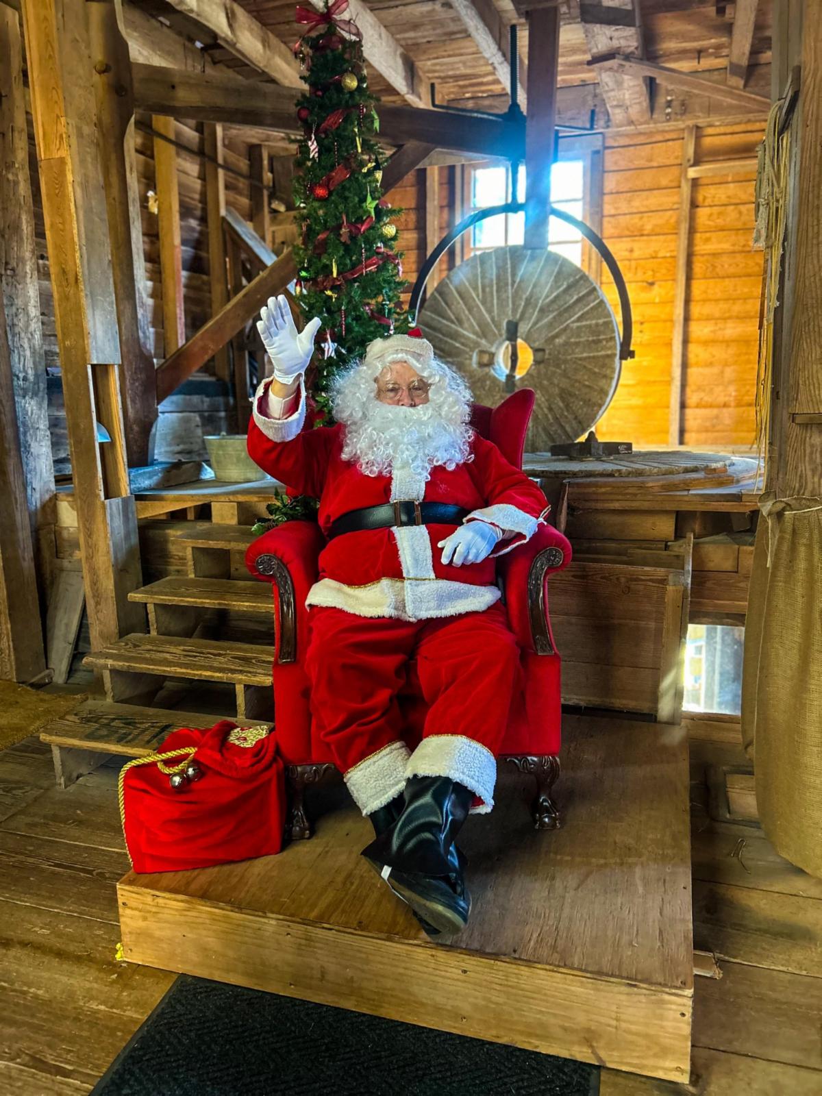 Photo of man dressed as Santa inside the gristmill and waving hello