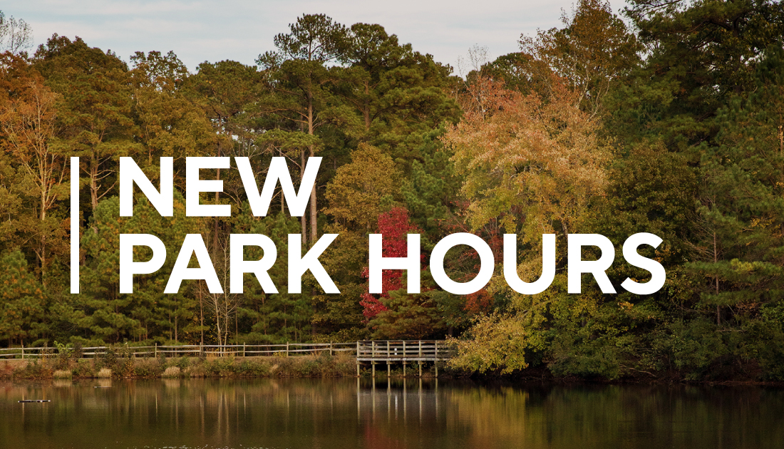 Image of trees with fall colors in background with text saying New Park Hours