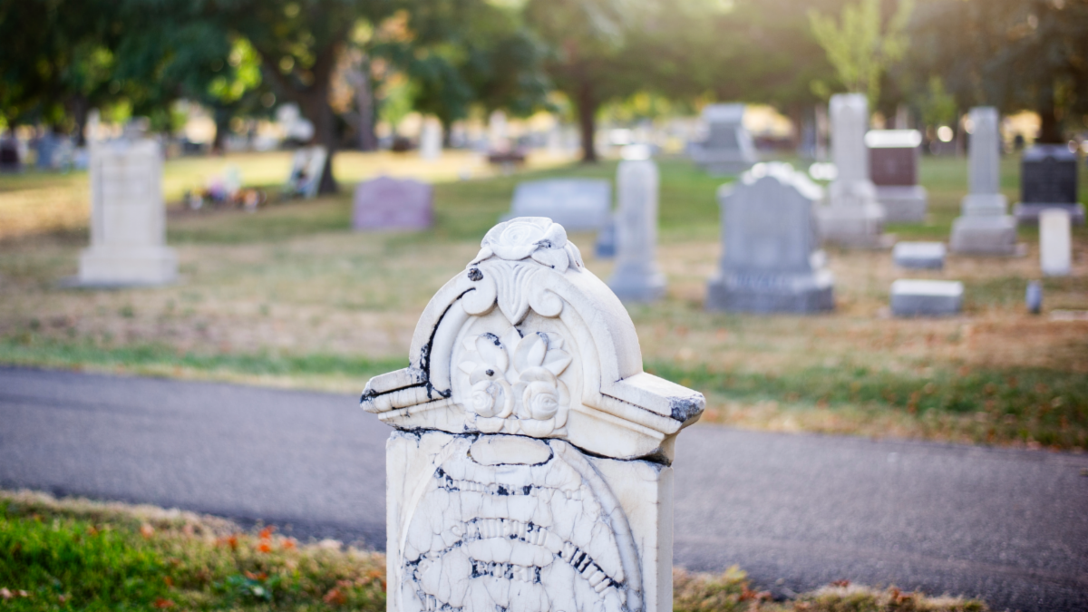 A headstone in a cemetery at dusk