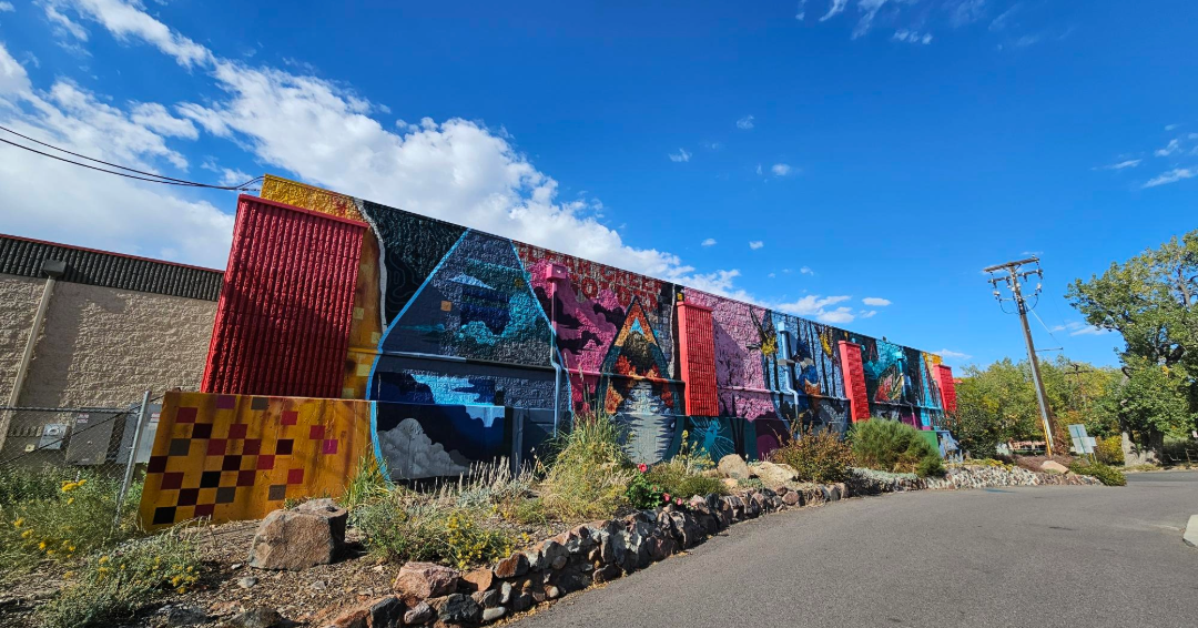 A mural on the exterior of a building underneath a blue sky