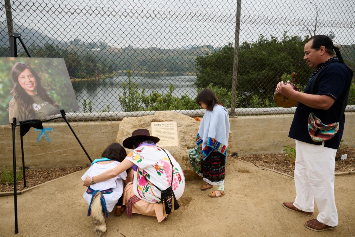 A man gives an indigenous blessing to the new Hollywood Reservoir Pollinator Garden while a woman and two children read the plaque commemorating Cindy MontaÃ±ez to whom the garden is dedicated
