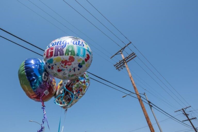 A set of graduation mylar balloons with power lines in the background. 