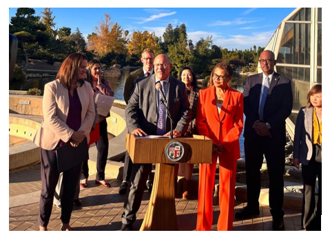 Group of people standing at a podium outside.