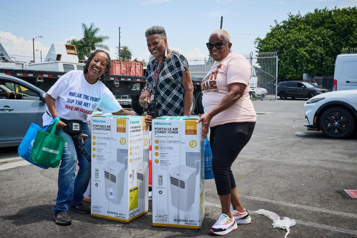 Smiling LADWP customers pose with portable air conditioning units they received for free at a Cool LA Heat Relief for Seniors event.