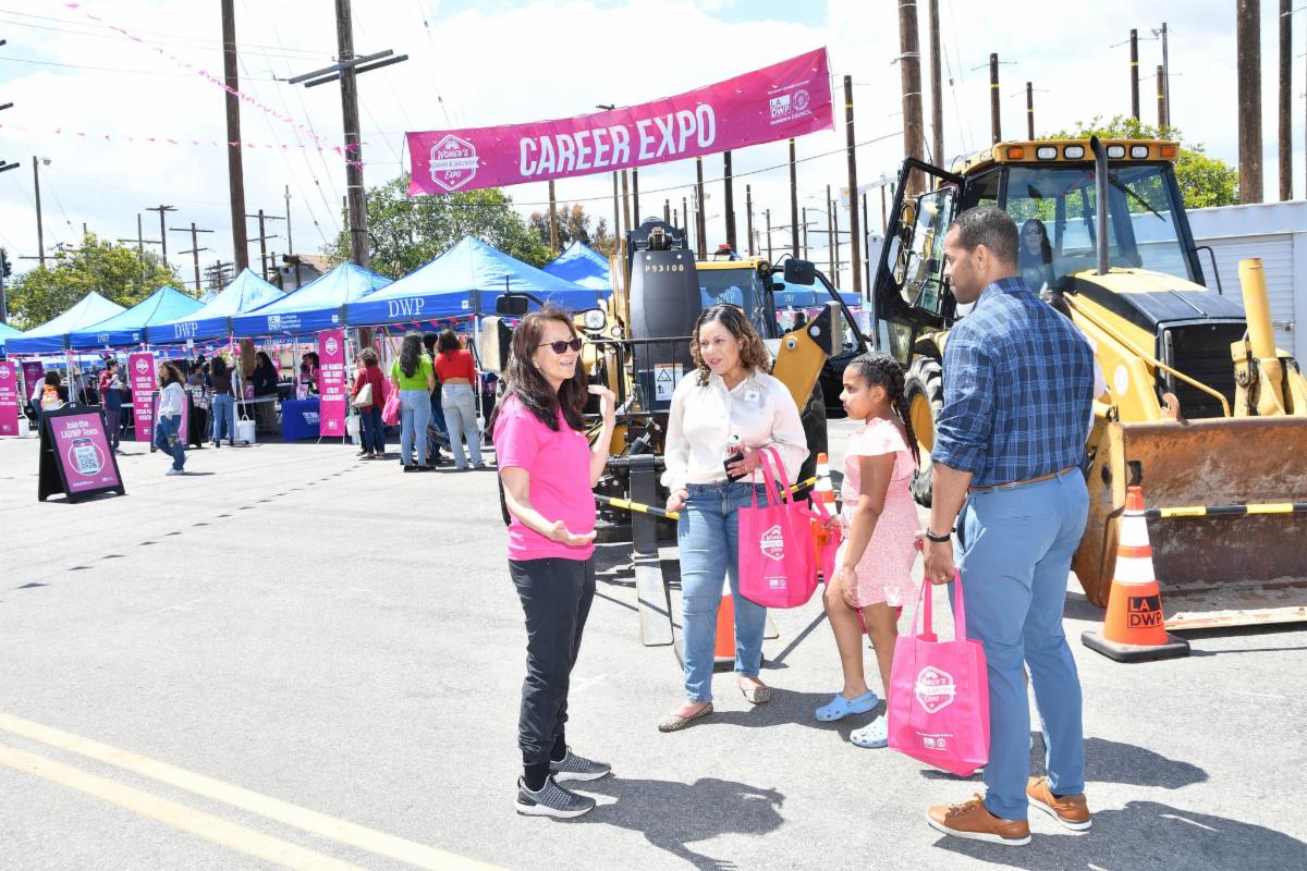 Woman speaking with a family in front of a Career Expo banner.