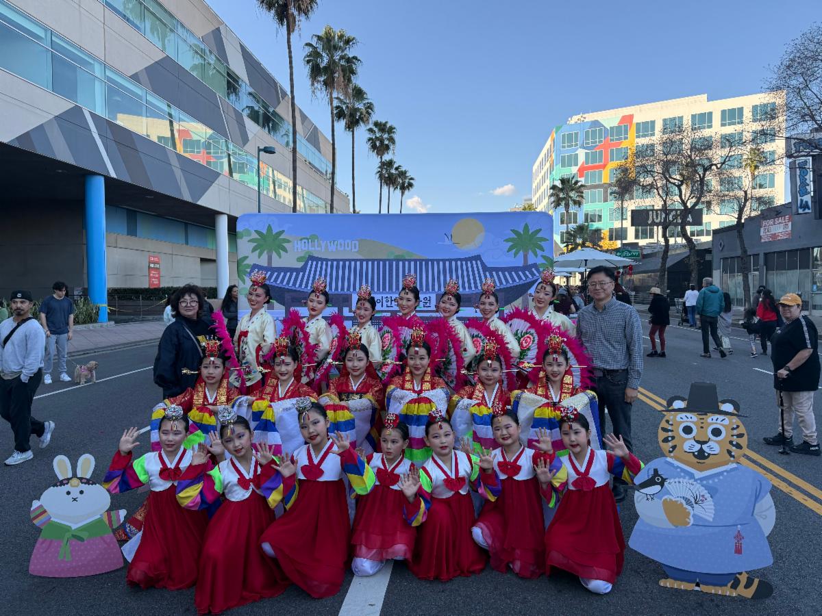 Group of women in red and white dresses posing for a picture outdoors in the street.&nbsp;